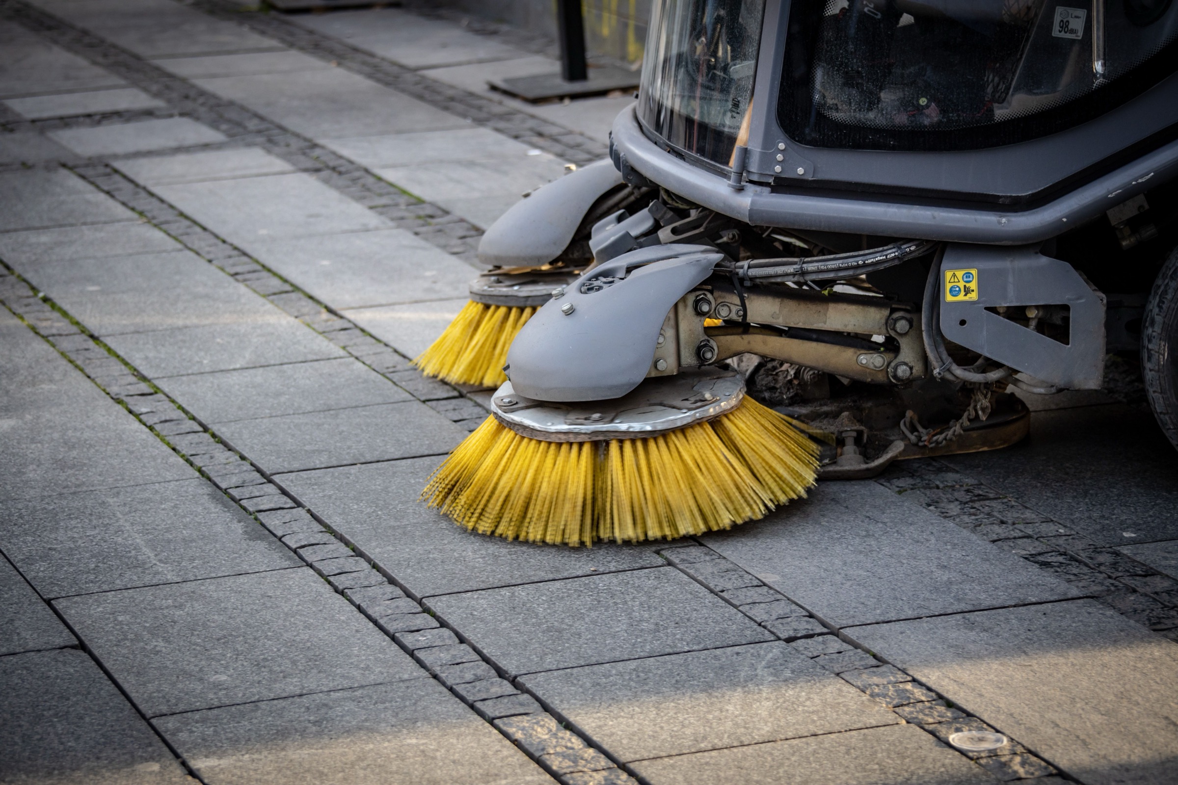 Bright yellow brushes on the front of a street sweeping machine